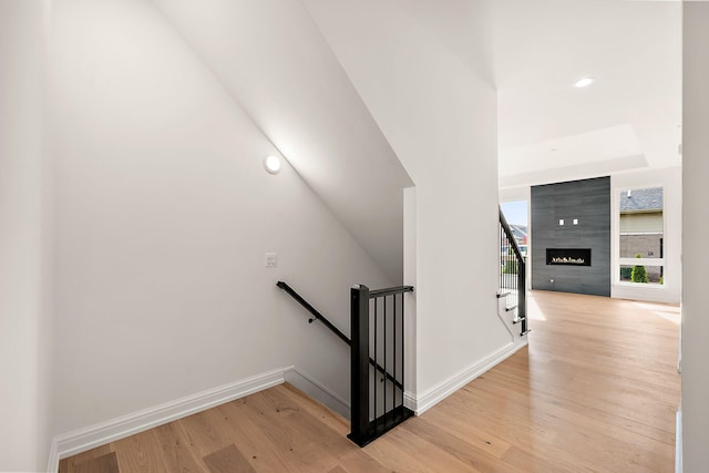 staircase featuring a tile fireplace and wood-type flooring