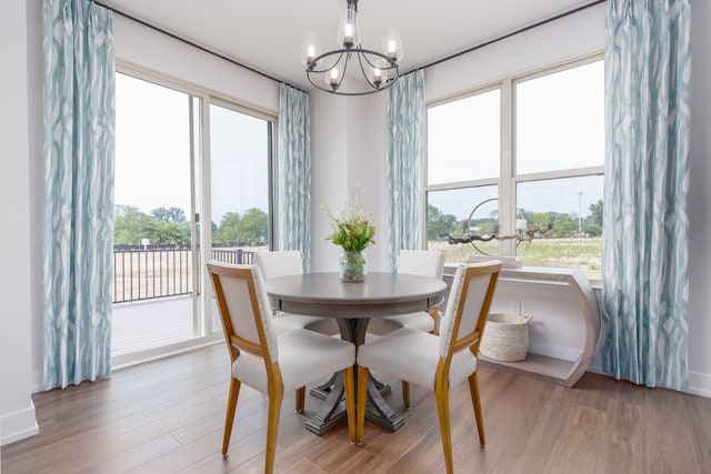 dining area with hardwood / wood-style floors, a wealth of natural light, and a notable chandelier