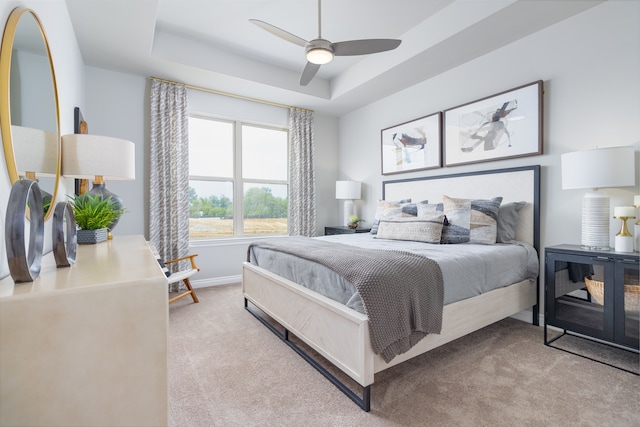 carpeted bedroom with ceiling fan and a raised ceiling