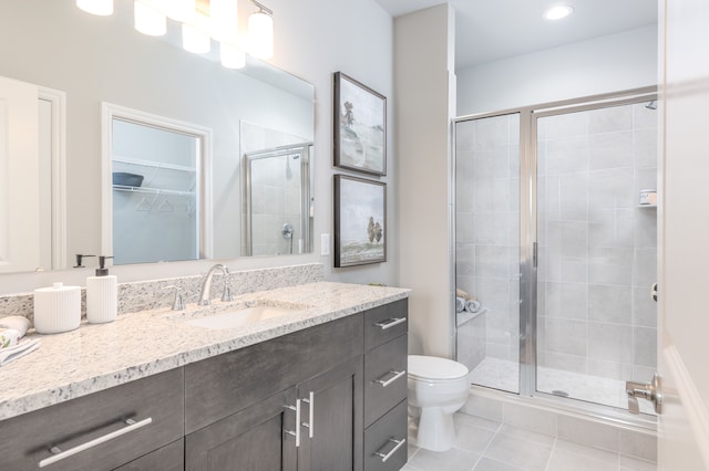 bathroom featuring tile patterned flooring, vanity, toilet, and a shower with shower door