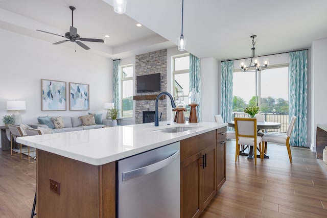 kitchen with stainless steel dishwasher, a center island with sink, sink, and light hardwood / wood-style flooring