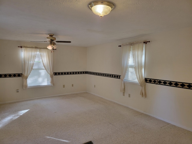 carpeted spare room featuring a ceiling fan, baseboards, and a textured ceiling