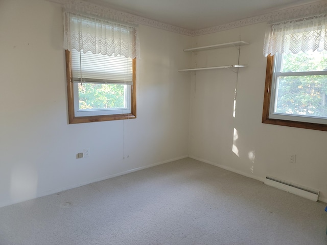 empty room featuring carpet flooring, plenty of natural light, and a baseboard heating unit