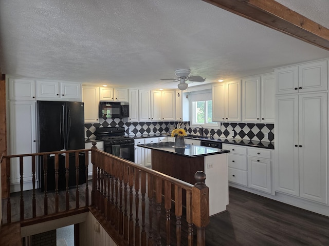 4085 N Cedar Lake Rd, Edmore, MI 48829 - kitchen with black appliances, dark countertops, a center island, white cabinets, and a textured ceiling