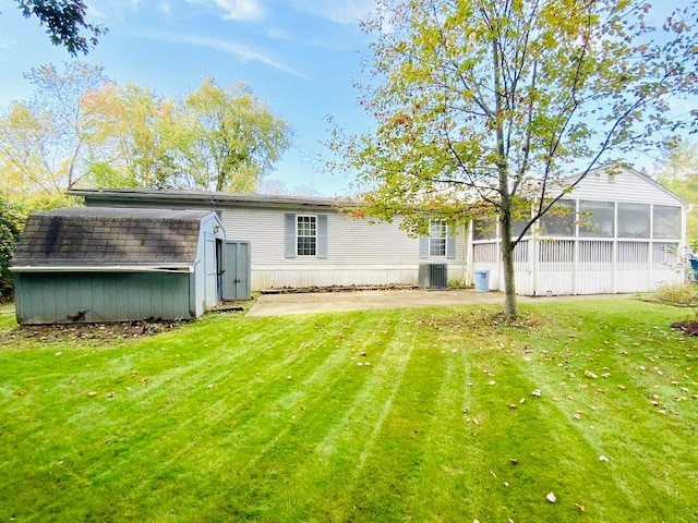 rear view of property featuring a yard, central AC, a storage shed, and a sunroom