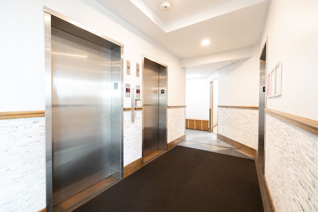 corridor featuring tile patterned flooring and elevator