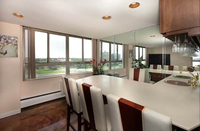 interior space featuring kitchen peninsula, plenty of natural light, a baseboard heating unit, and sink