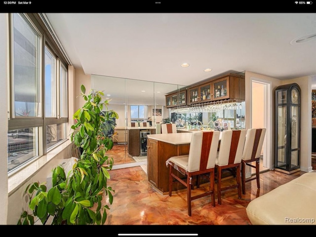 kitchen with plenty of natural light, beverage cooler, kitchen peninsula, and decorative light fixtures