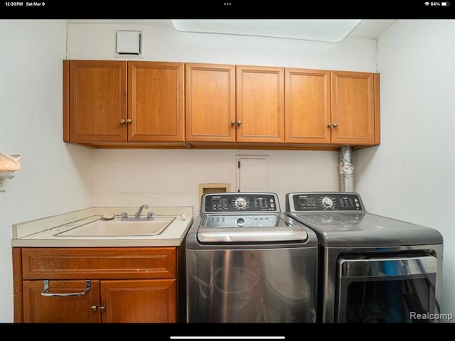 laundry area featuring washer and clothes dryer, cabinets, and sink