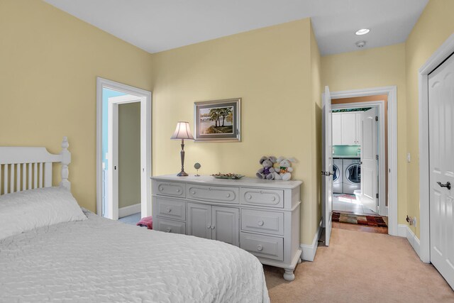 bedroom featuring washing machine and dryer, light colored carpet, and baseboards