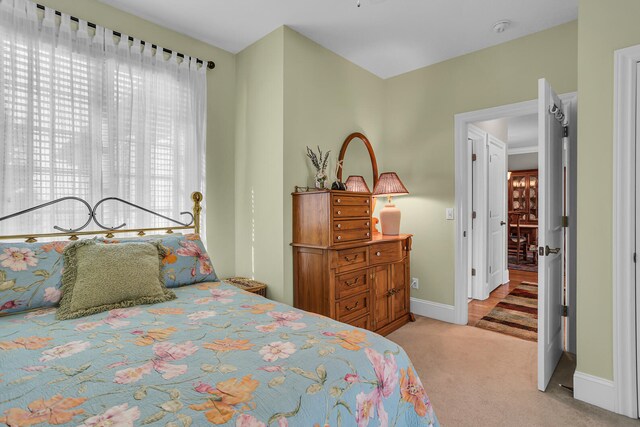 bedroom with baseboards and light colored carpet