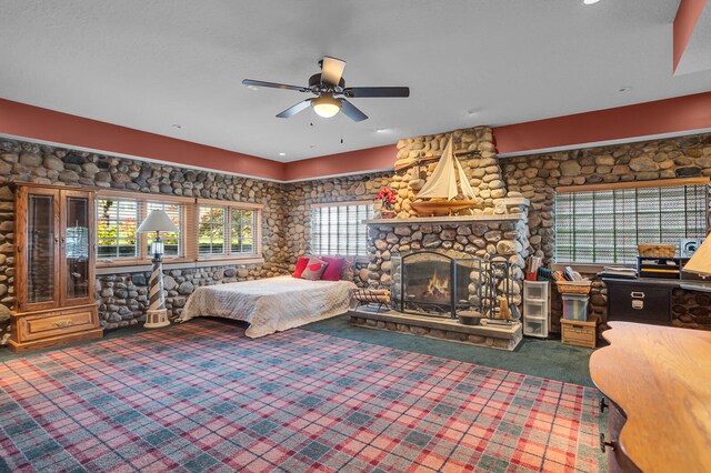 carpeted bedroom featuring a fireplace and a ceiling fan