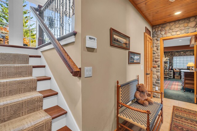 stairway featuring baseboards, wood ceiling, and tile patterned floors