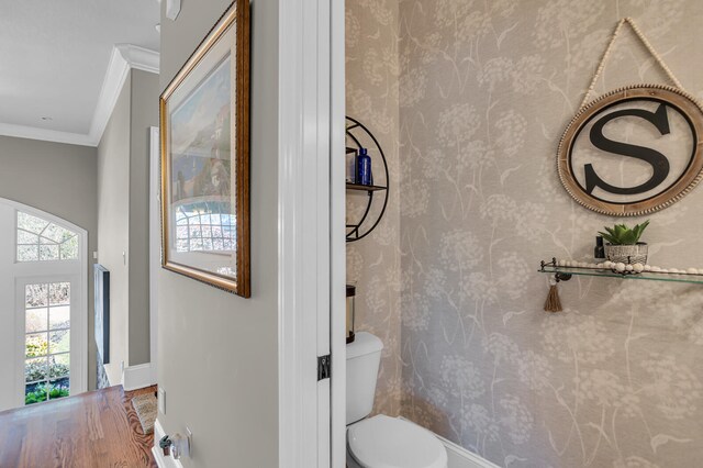 half bathroom featuring toilet, baseboards, and ornamental molding