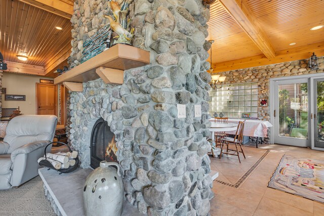 living area with wooden ceiling, a stone fireplace, beam ceiling, and light tile patterned floors