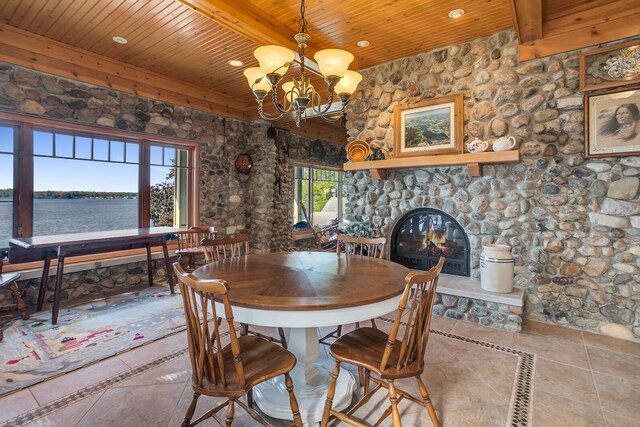 dining space with wood ceiling, a water view, a fireplace, and beamed ceiling