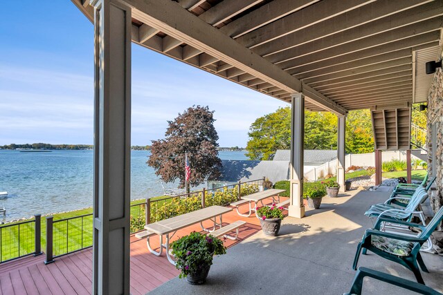 view of patio / terrace featuring a deck with water view and fence