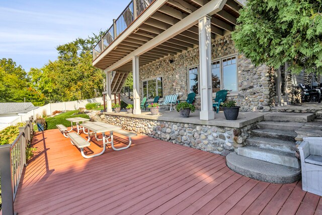 wooden deck featuring outdoor dining space, a fenced backyard, and stairway