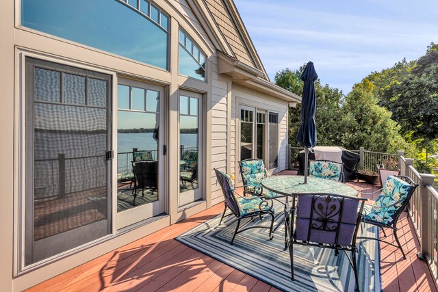 wooden deck featuring area for grilling, outdoor dining area, and a water view