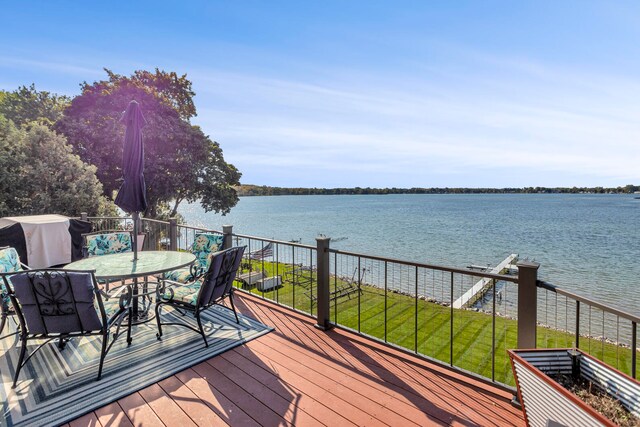 wooden terrace with a water view, a yard, and area for grilling