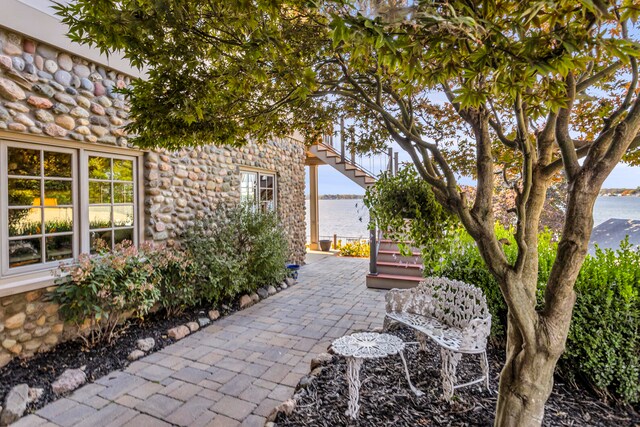 view of patio / terrace featuring a water view and stairway