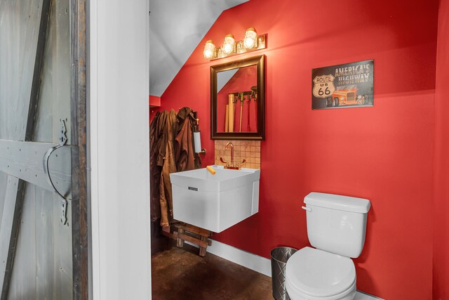 half bath featuring tasteful backsplash, a sink, toilet, and baseboards