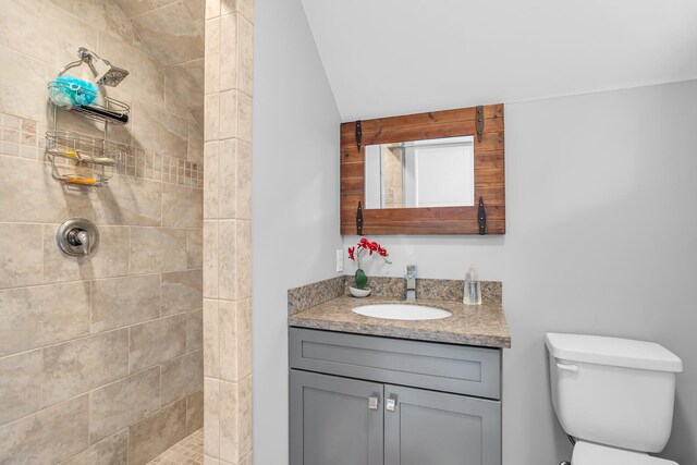 full bathroom with toilet, tiled shower, and vanity