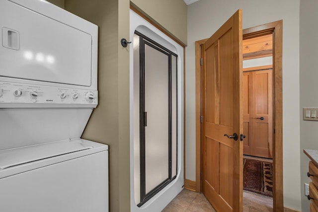 laundry area featuring laundry area, light tile patterned flooring, and stacked washer / drying machine