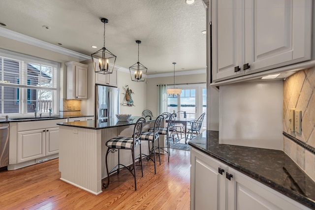 kitchen featuring a kitchen breakfast bar, appliances with stainless steel finishes, a sink, and white cabinets