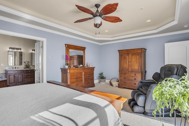 carpeted bedroom featuring ceiling fan, baseboards, ornamental molding, a tray ceiling, and ensuite bath