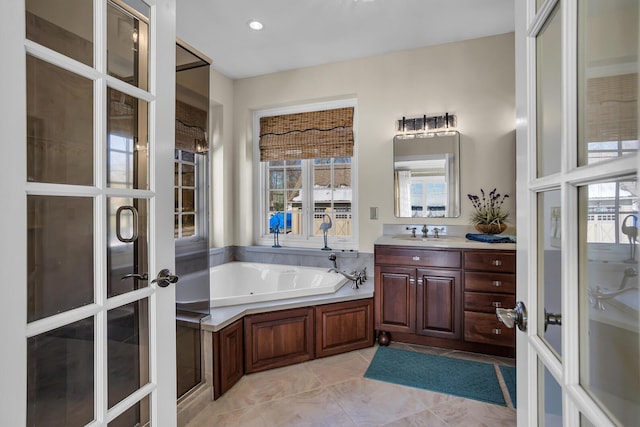 bathroom with a garden tub, tile patterned floors, french doors, and vanity