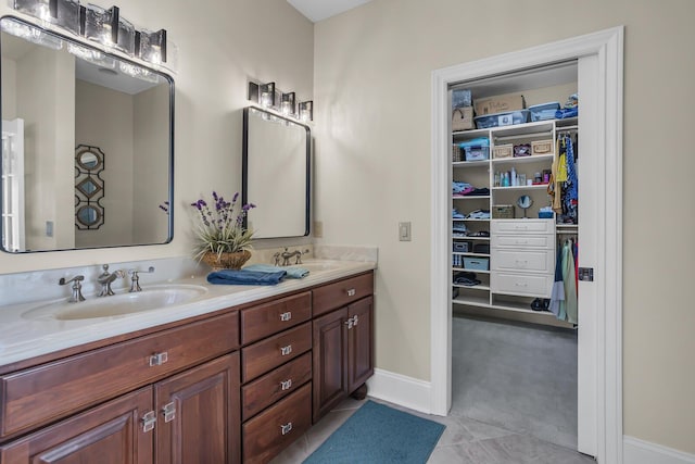 full bath featuring a sink, double vanity, a walk in closet, and tile patterned floors