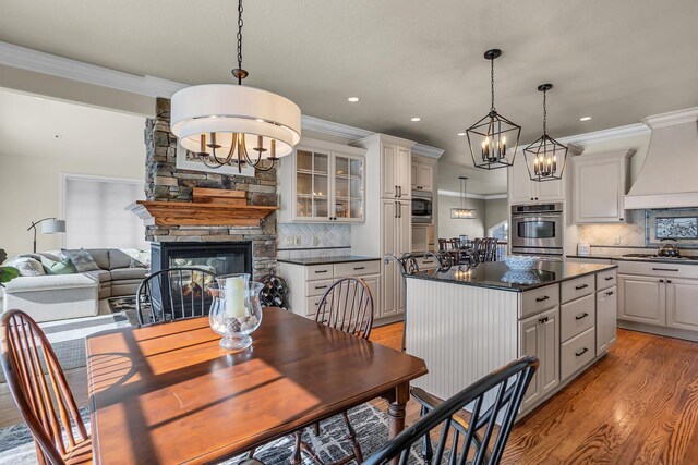 dining room with ornamental molding, a fireplace, light wood-style flooring, and an inviting chandelier