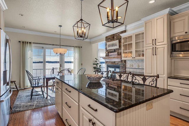 kitchen featuring a center island, pendant lighting, a water view, glass insert cabinets, and appliances with stainless steel finishes