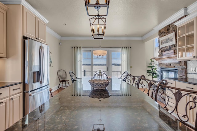 unfurnished dining area featuring a textured ceiling, a chandelier, crown molding, and a stone fireplace