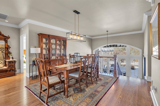 dining area featuring a notable chandelier, visible vents, baseboards, ornamental molding, and light wood-type flooring