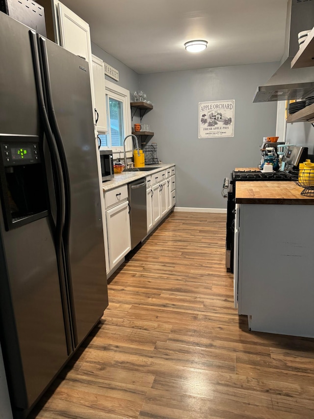 kitchen featuring white cabinets, stainless steel appliances, range hood, and light wood-type flooring