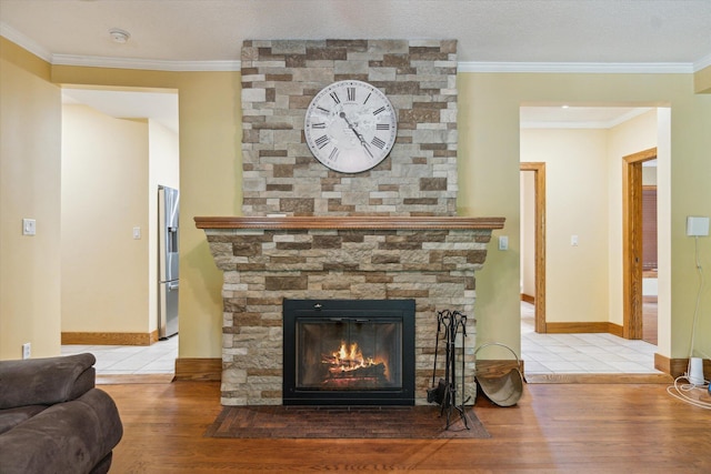 room details featuring a stone fireplace, wood-type flooring, stainless steel refrigerator with ice dispenser, and ornamental molding