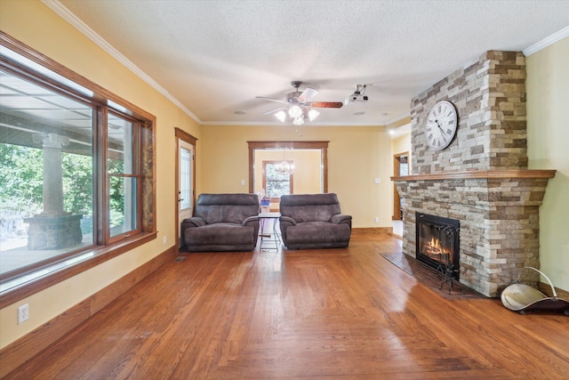 unfurnished living room featuring ceiling fan, a fireplace, ornamental molding, and a textured ceiling