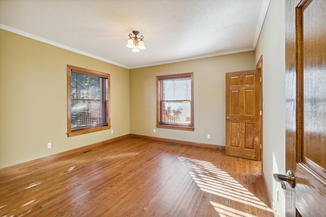 unfurnished room with plenty of natural light, light hardwood / wood-style floors, a textured ceiling, and ornamental molding