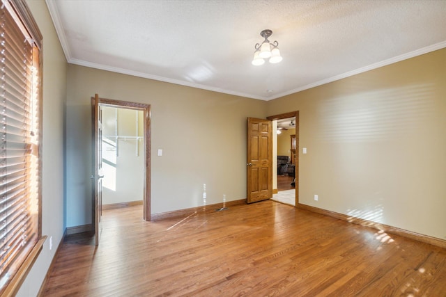 unfurnished room with a textured ceiling, ceiling fan, light wood-type flooring, and crown molding