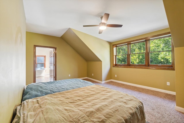 bedroom featuring light carpet, ensuite bath, vaulted ceiling, and ceiling fan