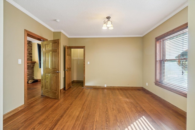 spare room featuring crown molding, hardwood / wood-style floors, and a textured ceiling