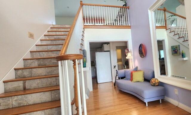 5578 Lake Shore Dr, Weidman, MI 48893 - stairs featuring a towering ceiling, wood finished floors, and baseboards