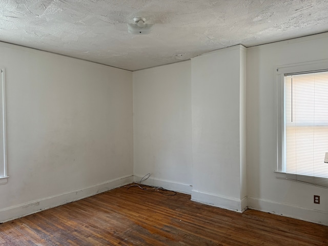 empty room featuring dark wood-type flooring and a textured ceiling