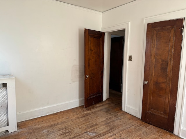 unfurnished room featuring wood-type flooring and ornamental molding