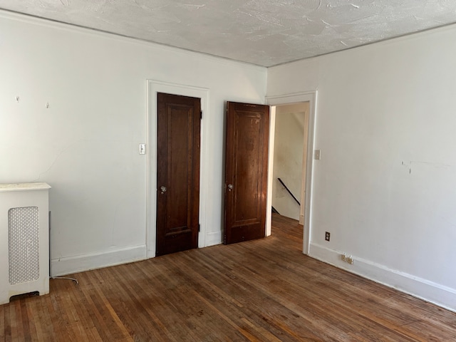 spare room with a textured ceiling and dark wood-type flooring