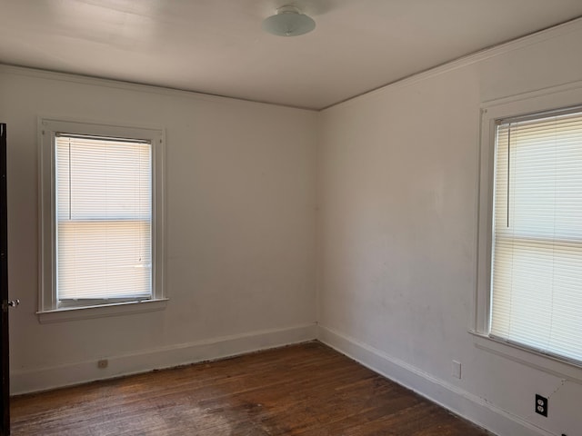 empty room with dark hardwood / wood-style floors and ornamental molding