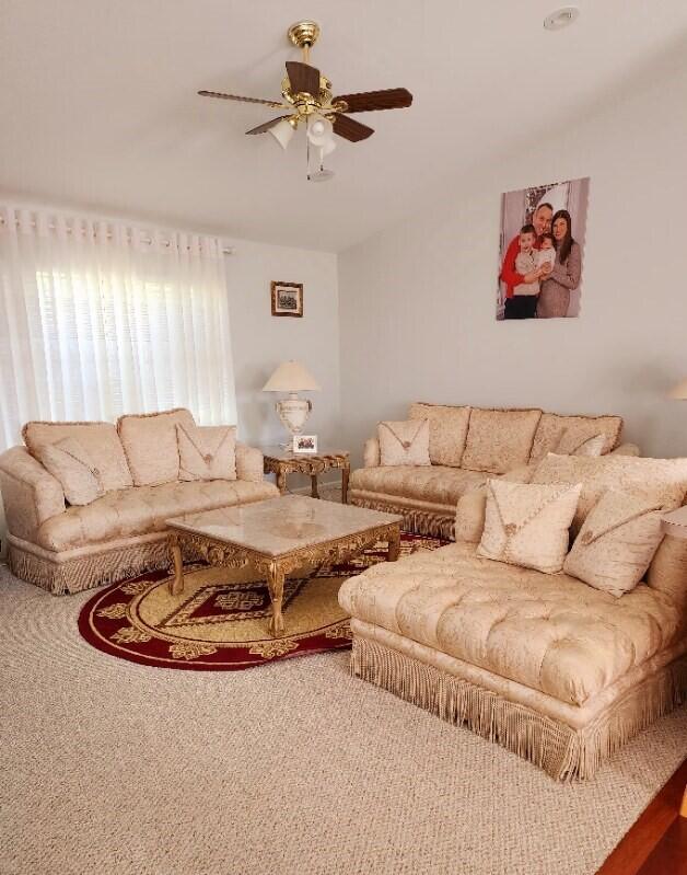 carpeted living room with ceiling fan