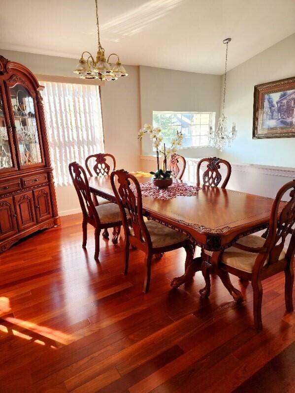 dining space with hardwood / wood-style flooring, vaulted ceiling, and a chandelier